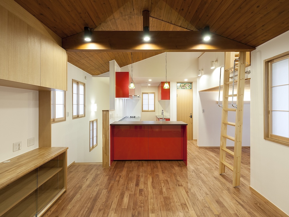 Open-concept kitchen with a red island, white countertops, and a wood-beamed vaulted ceiling.