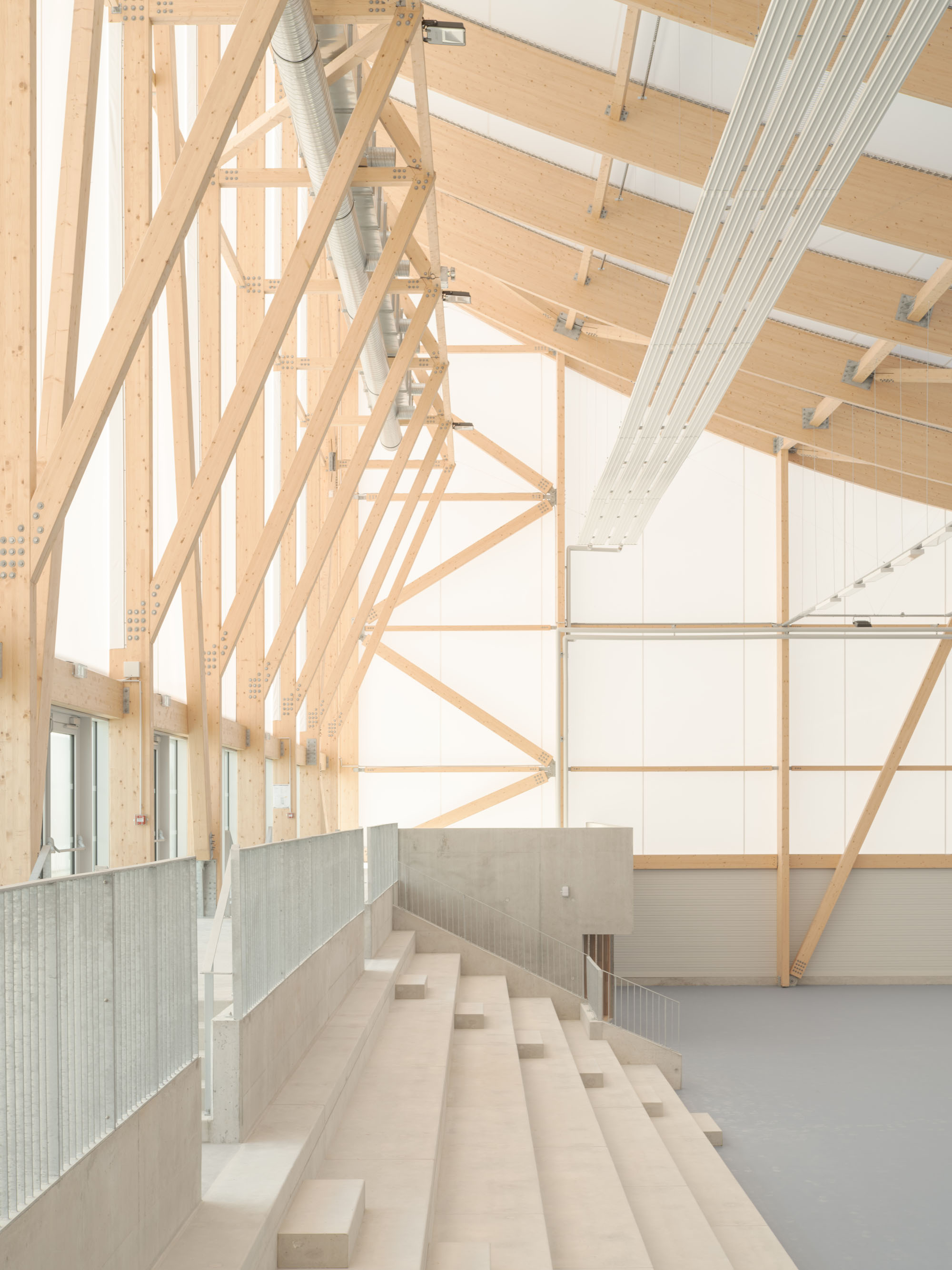 Interior with exposed wooden scaffolding and diagonal beams, metal ducts, and a concrete stairway running beside a water-filled channel.