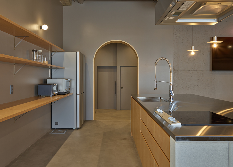 Modern kitchen with an island, stainless sink and gooseneck faucet, and an arched doorway at the back.